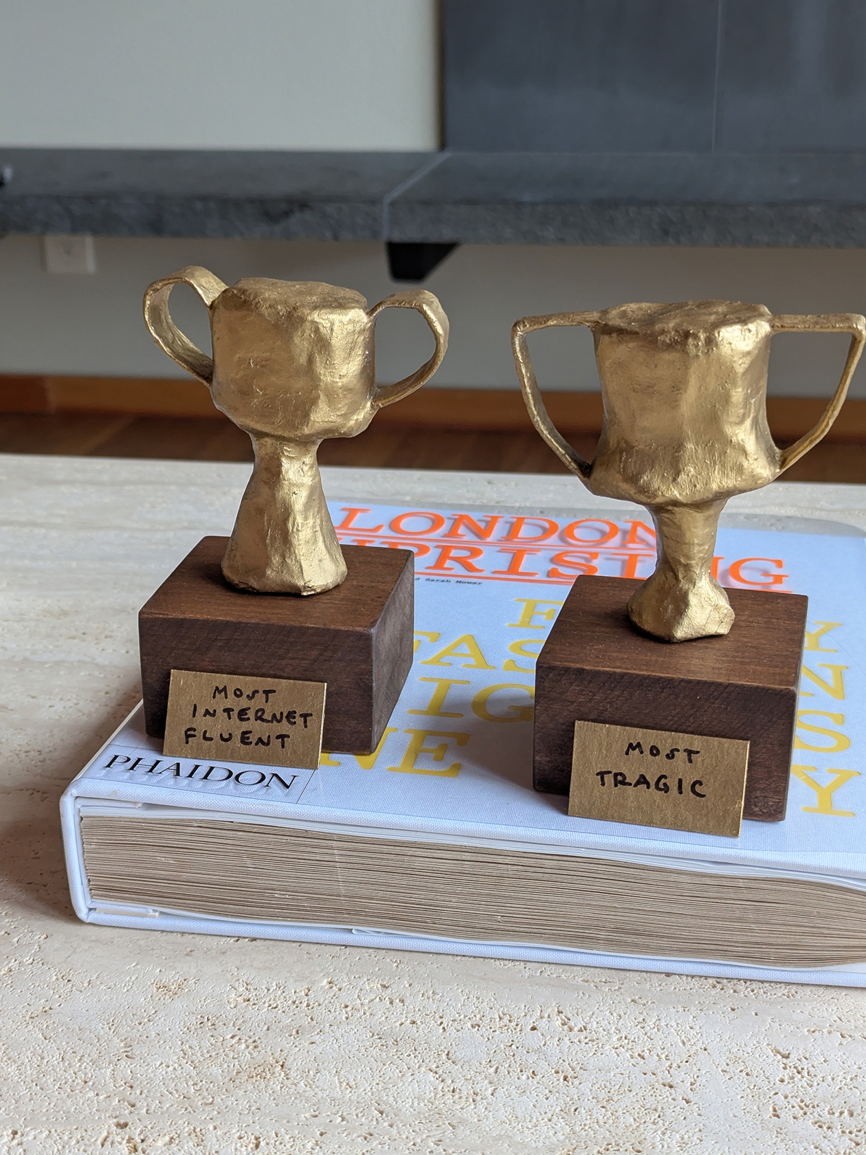 Two handmade trophies painted gold and mounted on walnut stained wood blocks.