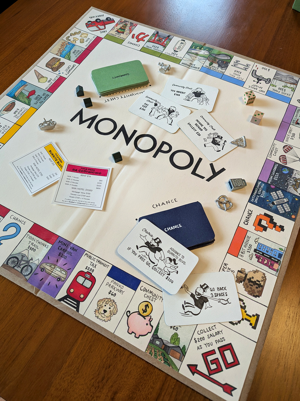 Handmade monopoly game board with hand illustrated squares and custom inked chance and community cards.